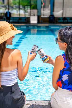 Two friends sip on Cowbell Brewing Co. beer at the Sheraton Centre Toronto pool Two friends sip on Cowbell Brewing Co. beer at the Sheraton Centre Toronto pool