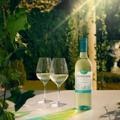 A bottle of Stoneleigh with two glasses in a garden