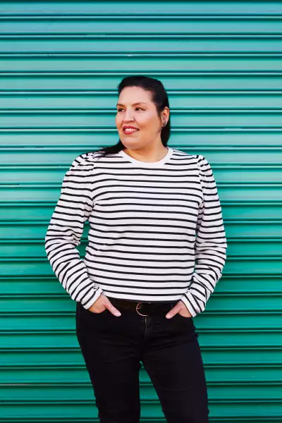 Carrie Rau, chef, sommelier and co-founder of Vinequity, stands in front of a green background