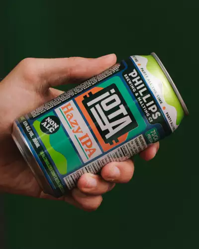 Phillips Brewing | A hand holds a can of iOTA Non-Alc Hazy IPA