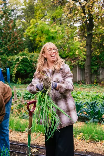 Don Alfonso's urban farm at Casa Loma | Editor Katie Bridges smiles with a bunch of freshly pulled scallions Casa Loma's urban farm