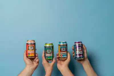 iOTA non-alcoholic beer | Three hands hold cans of iOTA non-alcoholic beer lineup from Phillips Brewing