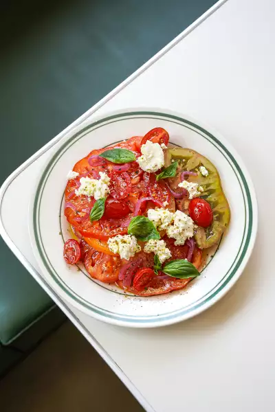 Juicy heirloom tomatoes sprinkled with globs of vegan feta on the summer prixe fixe menu at Stefano's Diner