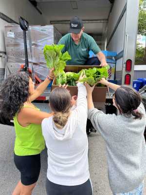 A group of Second Harvest volunteers unpacking lettuce from a truck A group of Second Harvest volunteers unpacking lettuce from a truck