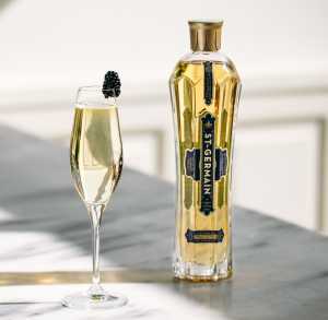 A cocktail made with St-Germain Elderflower Liqueur next to a bottle A cocktail made with St-Germain Elderflower Liqueur next to a bottle