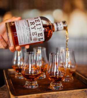 A bottle of Reifel Rye being poured into glasses A bottle of Reifel Rye being poured into glasses