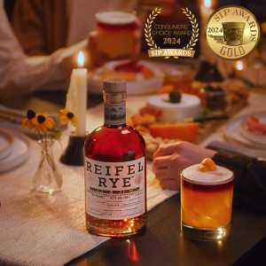 A bottle of Reifel Rye with a sour cocktail on a dinner table spread A bottle of Reifel Rye with a sour cocktail on a dinner table spread