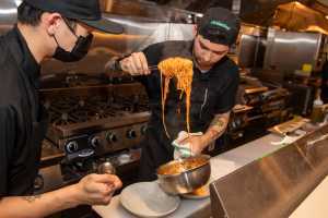 Two chefs serve spaghetti at the chef's counter at Occhiolino Toronto Two chefs serve spaghetti at the chef's counter at Occhiolino Toronto