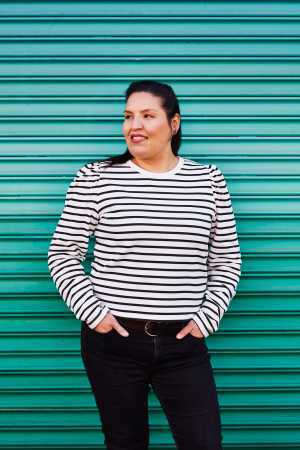 Carrie Rau, chef, sommelier and co-founder of Vinequity, stands in front of a green background
