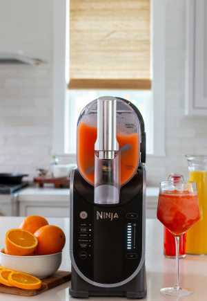 The Ninja Shark Slushi | The Ninja Shark Slushi Frozen Drink Maker sits on a countertop with oranges and a slushy drink