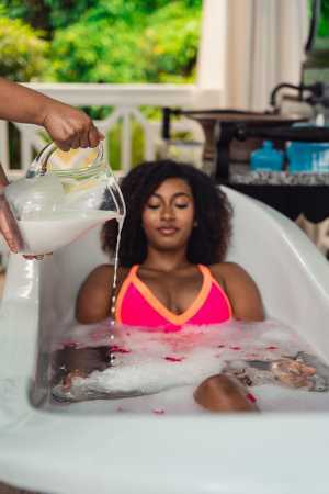 Relax in St. Kitts | A jug of water is poured onto a woman in an outdoor bath tub in St. Kitts