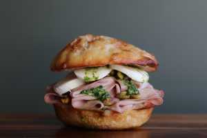 Neighbourhood Gems on DoorDash | A hand holds La Morta, a sandwich at Leslie's Sandwich Room