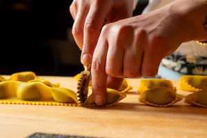 Pasta Privato | A hand uses a pasta wheel to cut fresh ravioli