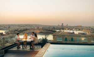 Malta's Michelin moment | A group eat al fresco on a rooftop beside a pool in Malta
