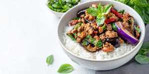 Thai Hom Mali rice | Thai basil eggplant with minced pork served over steamed jasmine rice, garnished with fresh basil leaves and dried red chilies in a white bowl