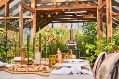 The Ooni Karu 12G pizza oven in a garden behind a set table with pizzas
