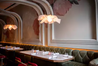 La Plume Toronto | Banquettes under floral chandeliers and a curving ceiling at La Plume in The Well