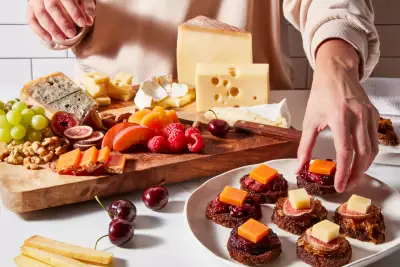 Hands making a spread of European cheeses