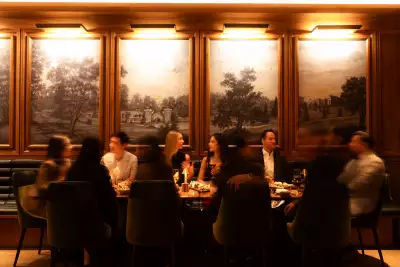 REIGN Toronto | A party of people enjoy dinner at REIGN with artwork as a backdrop