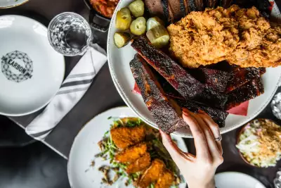 Best BBQ Toronto | A hand reaches for ribs on a platter at Carbon Bar