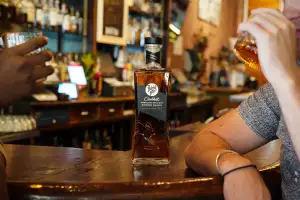 Rabbit Hole Kentucky bourbon on the bar with two people drinking Rabbit Hole Kentucky bourbon on the bar with two people drinking