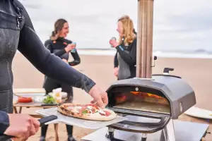 Taking a pizza out of the Ooni Karu 12G pizza oven at the beach Taking a pizza out of the Ooni Karu 12G pizza oven at the beach