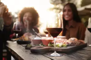 Food and wine pairings | A glass of wine on a table with food and a couple in the background