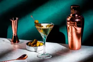 A martini with olives, a shaker tin, stirring spoon and jigger A martini with olives, a shaker tin, stirring spoon and jigger