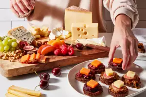 Hands making a spread of European cheeses