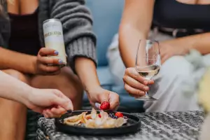 Nova Scotia wineries | Hands hold glasses of wine and enjoy snacks at Domaine de Grand Pr&eacute; winery in Nova Scotia