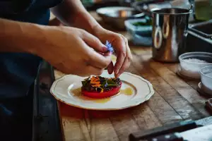 Farm-to-table dining in Qu&eacute;bec: A hand garnishes a meal with edible flowers at Escape Old Mill