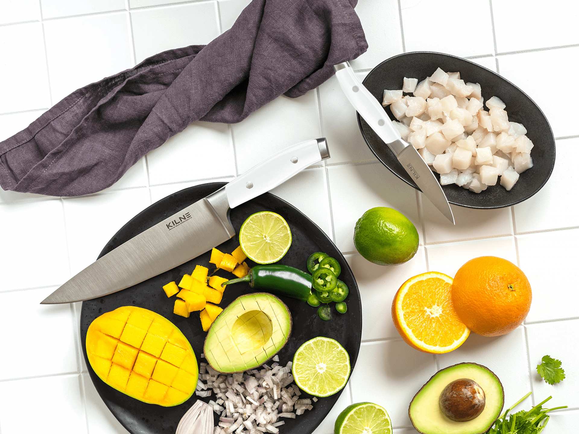 Kilne Ultimate Knife Set | White Kilne chef's knife and white paring knife with chopped vegetables and fruits Kilne Ultimate Knife Set | White Kilne chef's knife and white paring knife with chopped vegetables and fruits