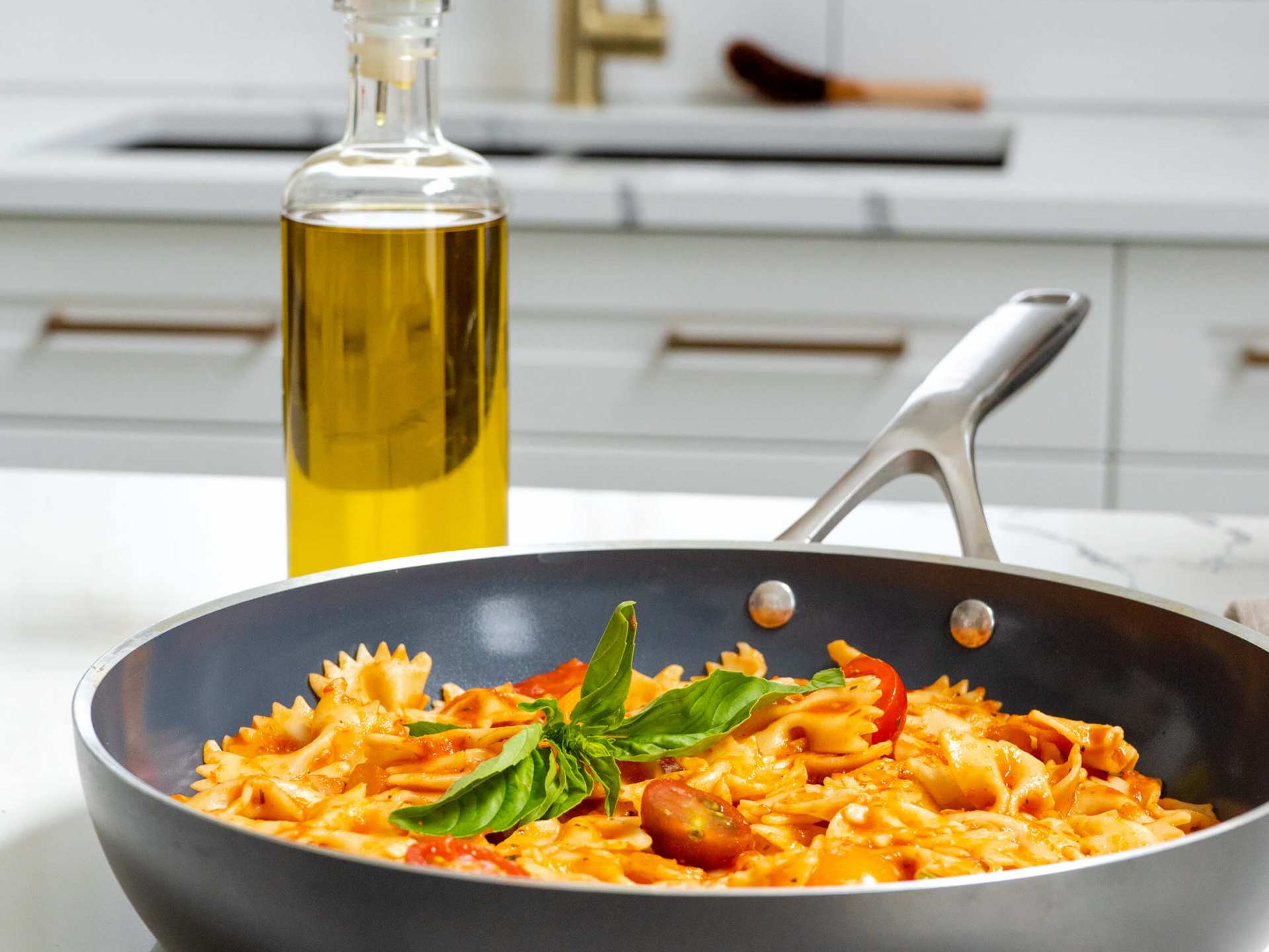 Kilne Everything Pan with ribbon pasta and a bottle of olive oil on a kitchen counter Kilne Everything Pan with ribbon pasta and a bottle of olive oil on a kitchen counter