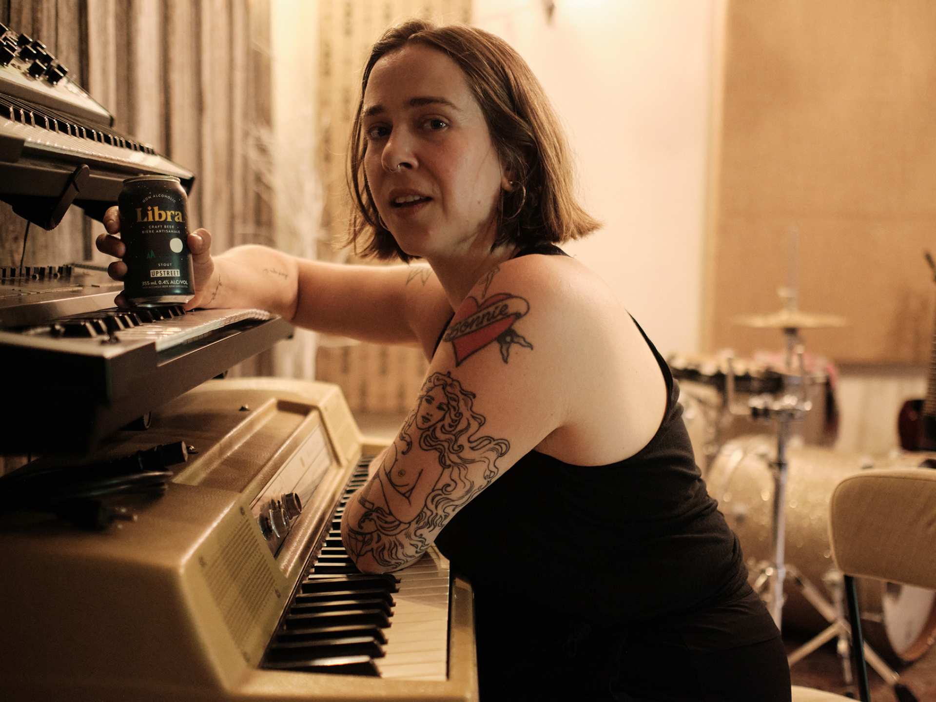 Serena Ryder leaning on her piano with a can of Libra non-alcoholic craft beer Serena Ryder leaning on her piano with a can of Libra non-alcoholic craft beer