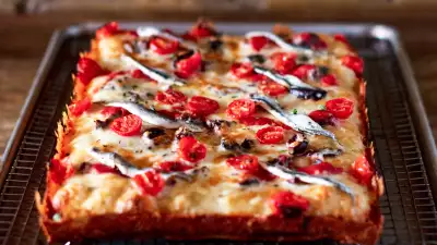 The best new restaurants in Toronto | Mediterranean Detroit-style pan pizza with boquerones, olives, tomatoes, cheese & tomato sauce at Gianna&rsquo;s Patties and Pies