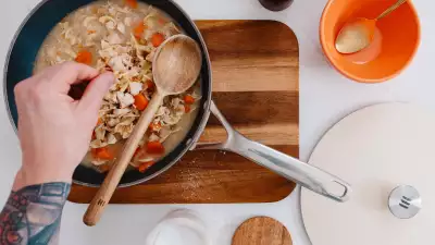 Kilne Everything Pan with pasta and a person sprinkling cheese on top