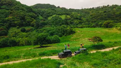 Relax in St. Kitts | People stand on top of jeeps against a mountainous backdrop in St. Kitts