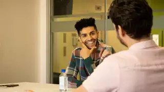 Mena Massoud | Aladdin actor Mena Massoud smiling and sitting at a table Mena Massoud | Aladdin actor Mena Massoud smiling and sitting at a table
