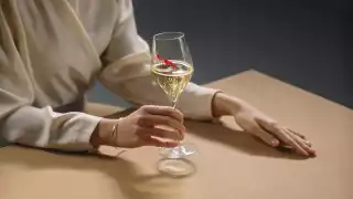 GH Mumm | A woman in a cream coloured blouse holds a glass of GH Mumm champagne
