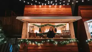 Elora Christmas Market | A woman peeks out of a chalet at the Elora Christmas Market