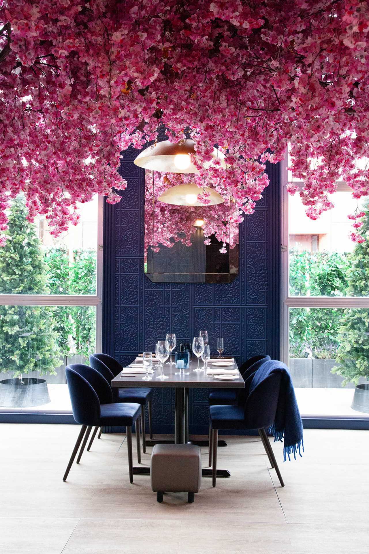 Via Allegro Ristorante | A table under pink flowers inside the glass-enclosed heated patio Via Allegro Ristorante | A table under pink flowers inside the glass-enclosed heated patio