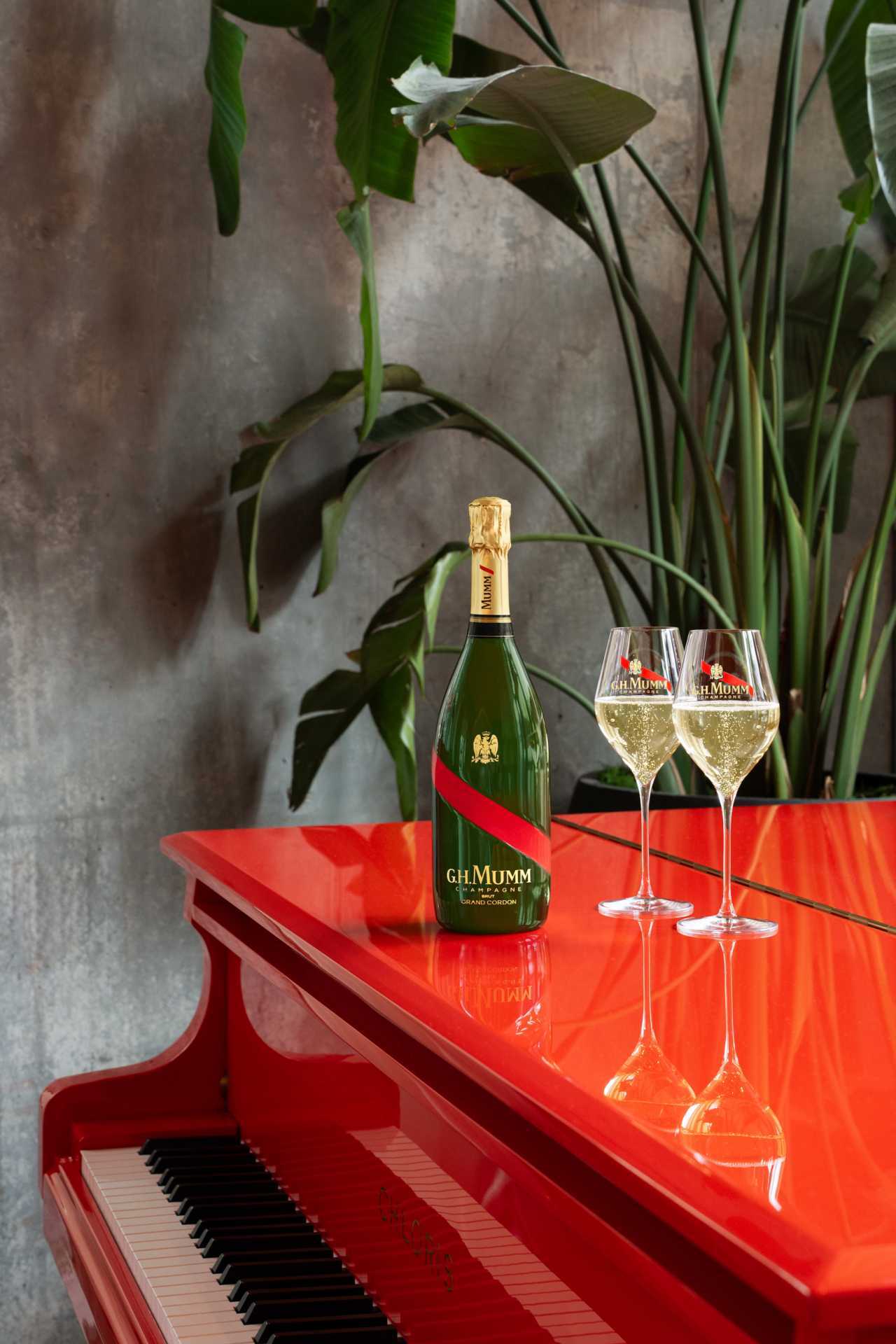 G.H.Mumm | Two glasses of champagne and a bottle of G.H.Mumm sits on a red piano G.H.Mumm | Two glasses of champagne and a bottle of G.H.Mumm sits on a red piano