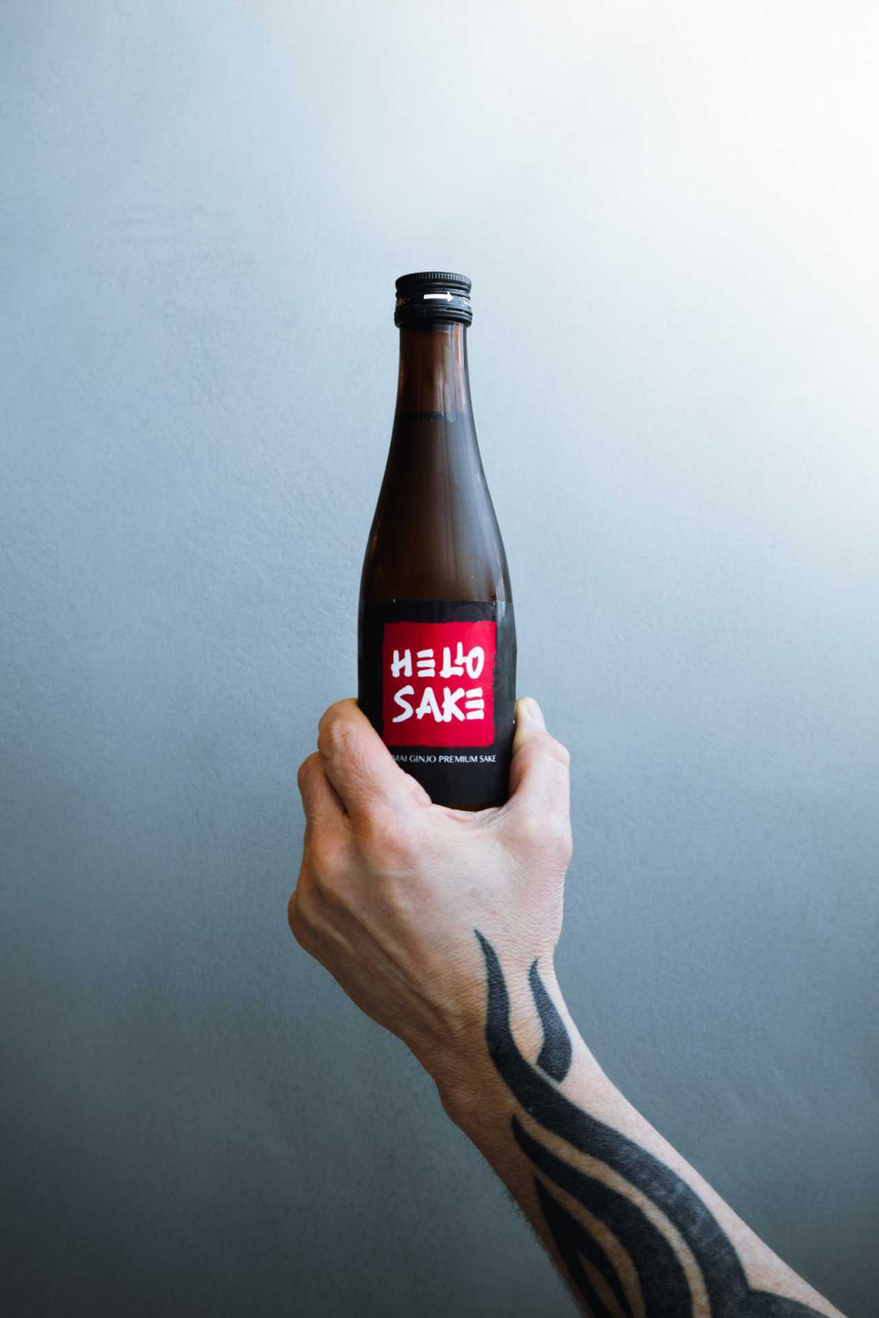 Hello Nori, King West, Toronto | A hand holds out a bottle of sake at Hello Nori Hello Nori, King West, Toronto | A hand holds out a bottle of sake at Hello Nori