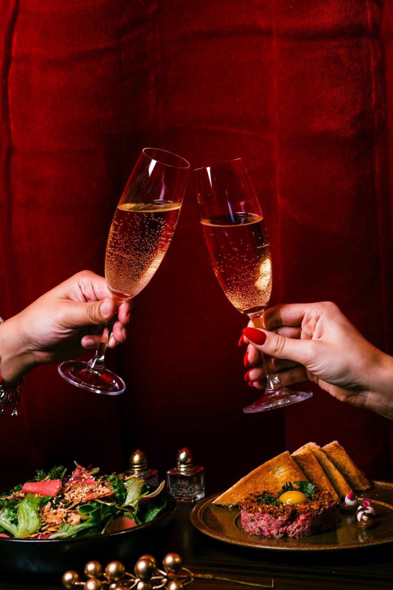Best Christmas bars and markets in Toronto | Two hands clink champagne glasses at Melody's at Gladstone House
