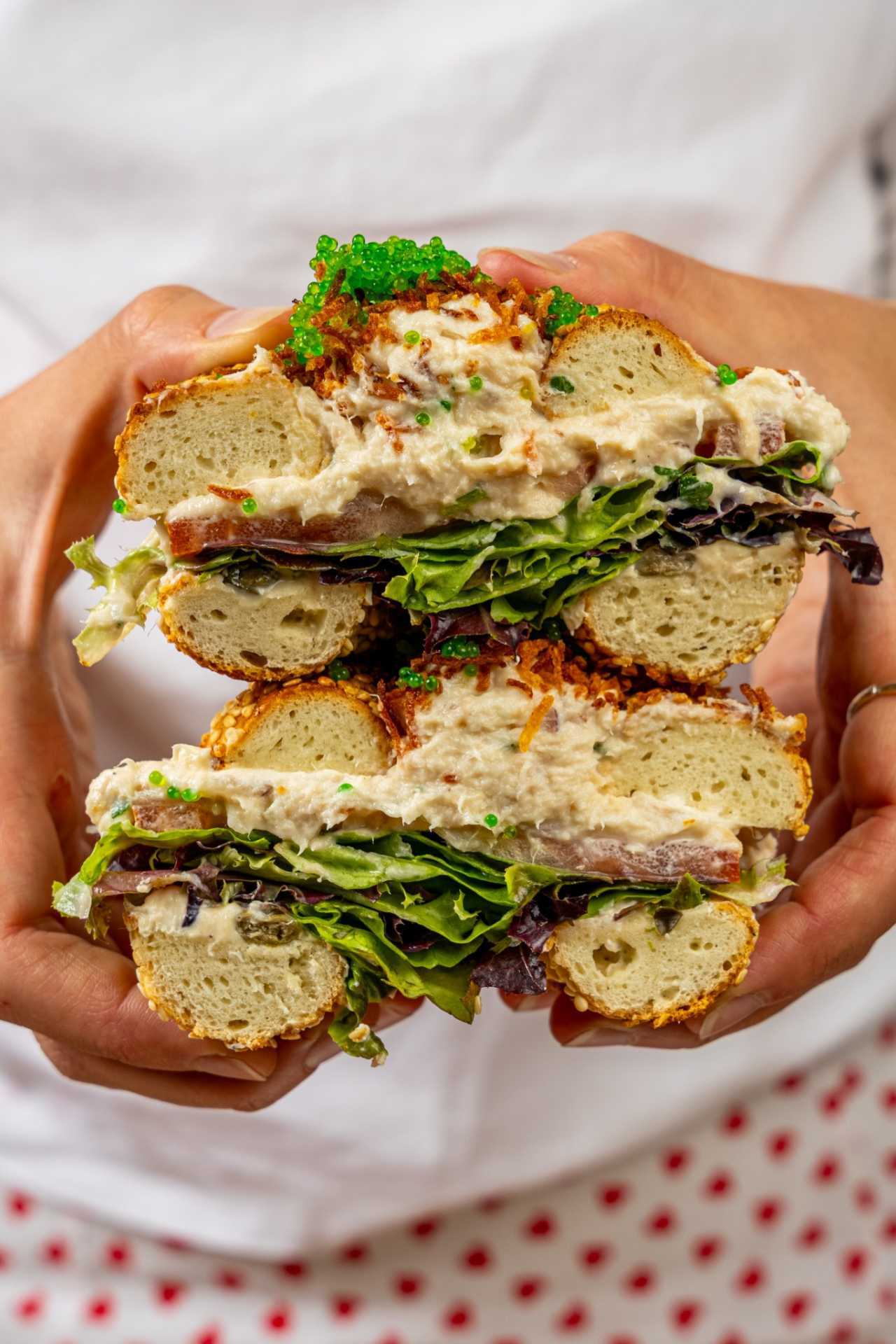 Farm-to-table dining in Qu&eacute;bec: A hand holds a stacked bagel open at Chez Greenberg