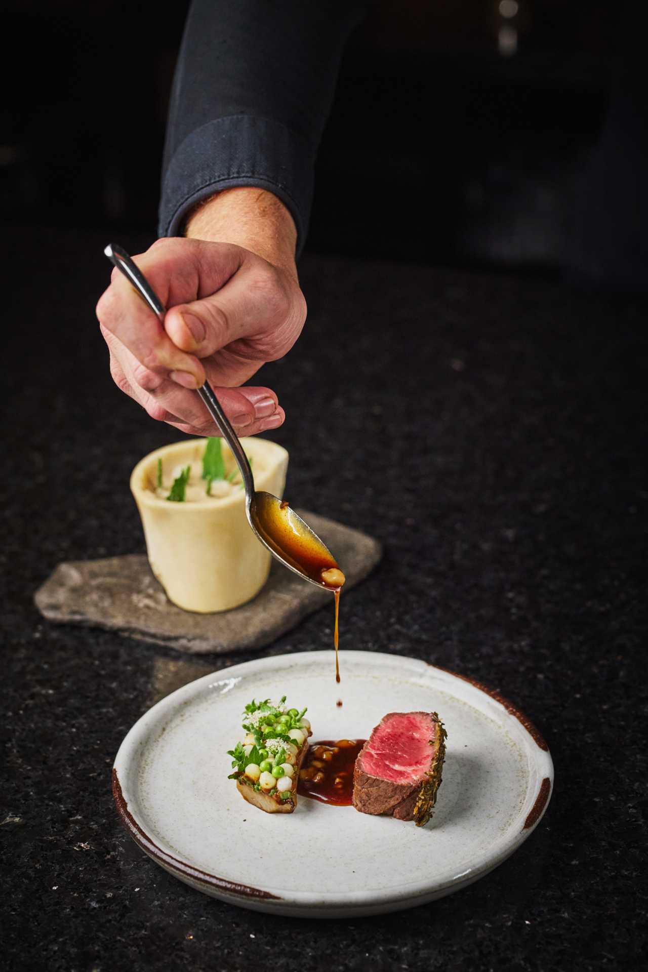 Farm-to-table dining in Qu&eacute;bec: A hand pours sauce at Tani&egrave;re&sup3; in Quebec City