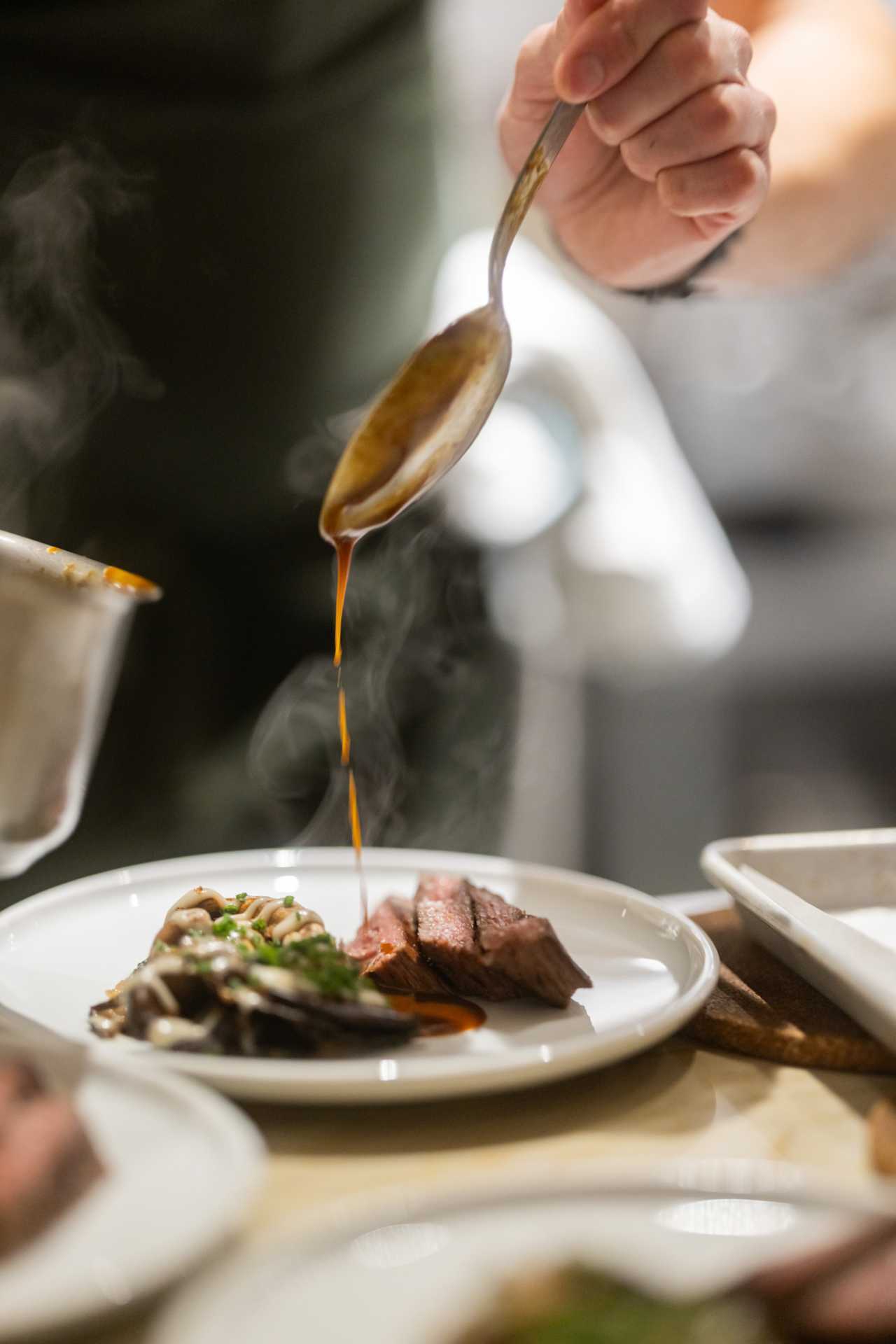 Farm-to-table dining in Qu&eacute;bec: A spoon pours a sauce onto a dish at Melba in Quebec City