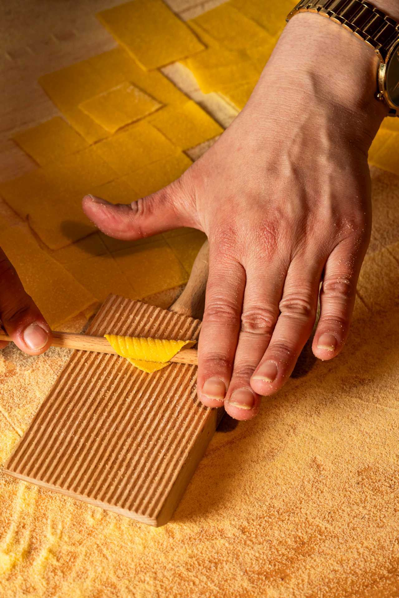 Pasta Privato Toronto | A hand rolls fresh pasta over a gnocchi board at Pasta Privato in Toronto