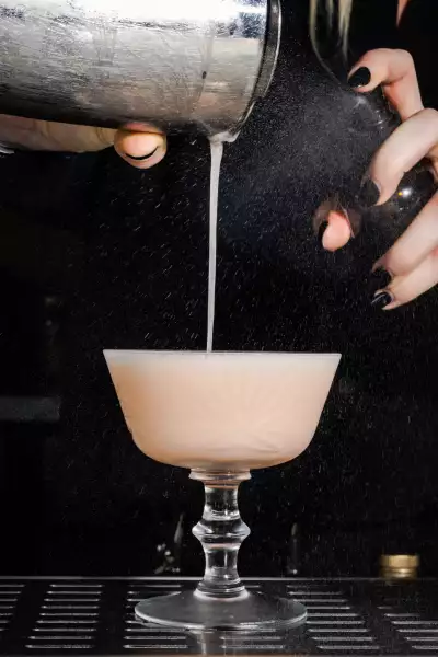 A bartender pours Aunt Spike, a peachy spin on a gin sour, at Lisbon Hotel