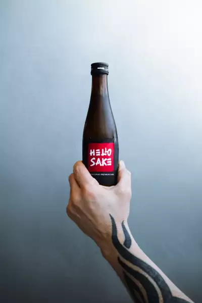 Hello Nori, King West, Toronto | A hand holds out a bottle of sake at Hello Nori